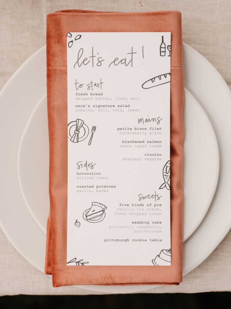 Custom illustrated wedding reception menu with handwritten typography and rust velvet napkin at a 320 Ranch Montana wedding