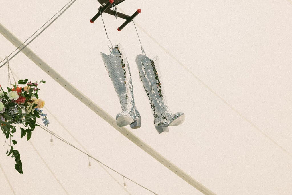 Mirrored disco cowboy boots hanging inside reception tent as playful Montana-inspired wedding decor detail at Bozeman celebration.